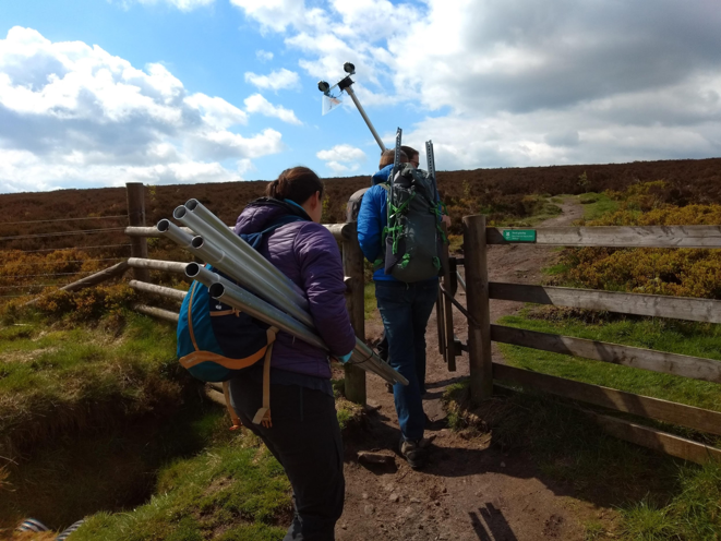 Volunteers James Bibby and Amy Bibby carry early version of Eva Crane funded mast system to field site.